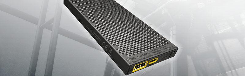 Extern SSD-enhet med kolmönstrad yta och gula USB-C-portar på mörk bakgrund